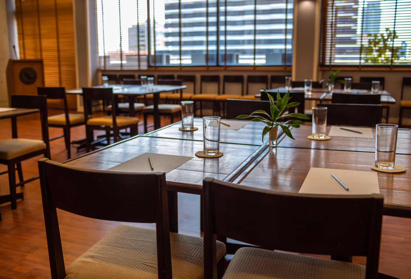 Long tables in the club room laid with glasses and notepads, the city through the windows